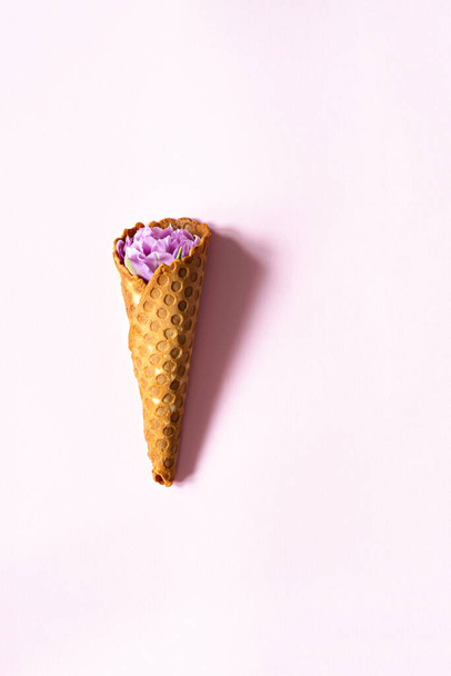 Вафельний конус з тюльпанами на рожевому тлі. Квіткове морозиво, весняна концепція з першими квітами
. - Фото, зображення
