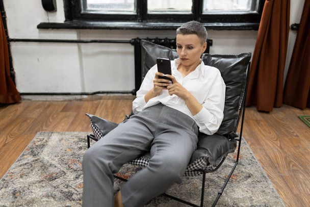 uma mulher de negócios com um corte de cabelo curto durante uma pausa para café relaxa no escritório. - Foto, Imagem
