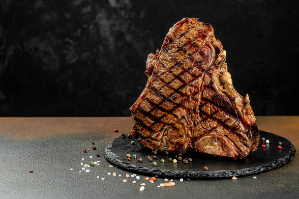 暗めの背景にスパイスの入ったTボーングリルビーフステーキ。レストランメニュー、食事、料理本のレシピ , - 写真・画像