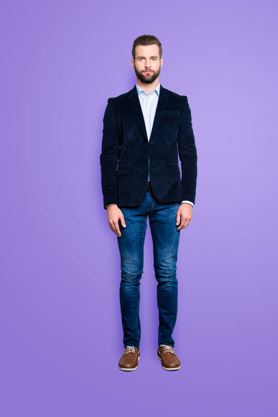 Full size body portrait, snap of attractive trendy teacher with stubble, looking at camera, isolated over grey background, wearing jacket, jeans, shirt. - Фото, изображение