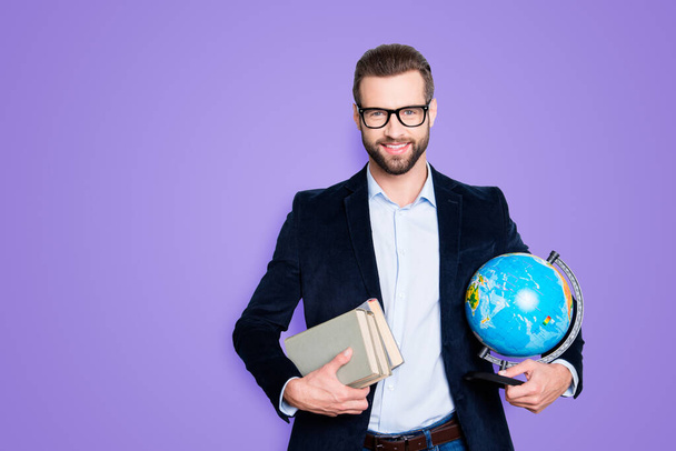 Portrait of stylish joyful teacher in shirt jacket with stubble having books and round globe, earth in hands, looking at camera, isolated on grey background. - Foto, Bild