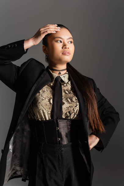 Trendy asian model in jacket and shirt with animal print posing isolated on grey  - Fotografie, Obrázek