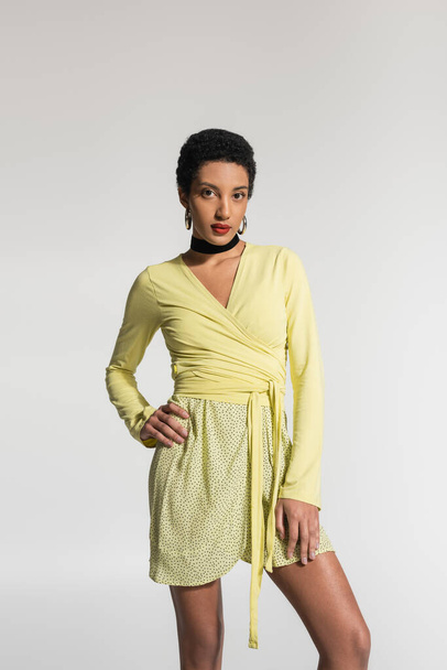 Young african american woman in yellow clothes posing isolated on grey  - Фото, зображення