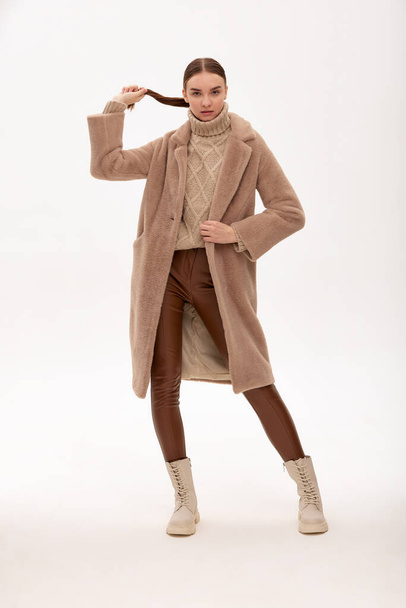 Moda mujer joven en un abrigo de piel sintética sobre un fondo gris - Foto, imagen