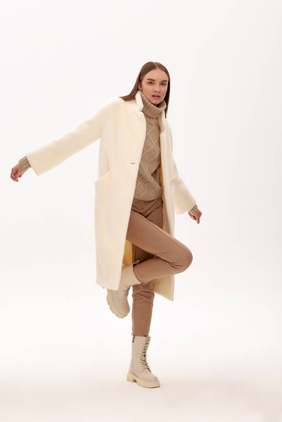 Mode jeune femme dans un manteau en fausse fourrure sur un fond gris - Photo, image