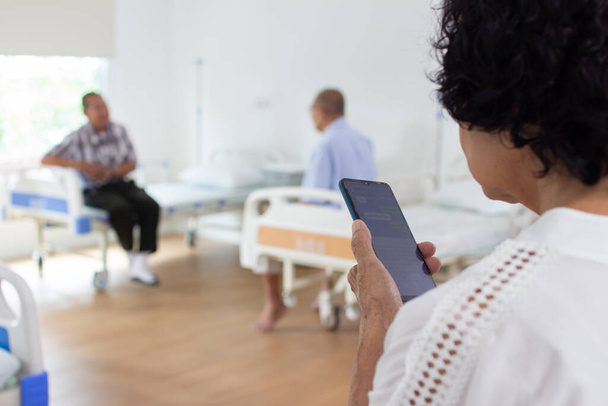 koncepcja domu opieki pielęgniarskiej. Starsza kobieta używa telefonu komórkowego. patrząc w kamerę - Zdjęcie, obraz