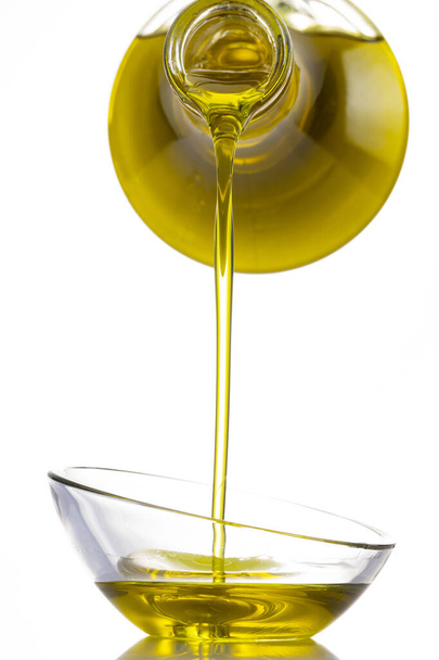 Organic olive oil pouring from carafe  into glass bowl - Photo, image