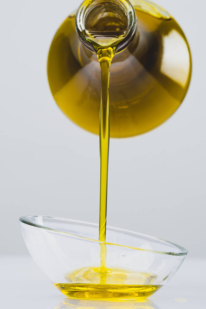 Organic olive oil pouring from carafe  into glass bowl - 写真・画像