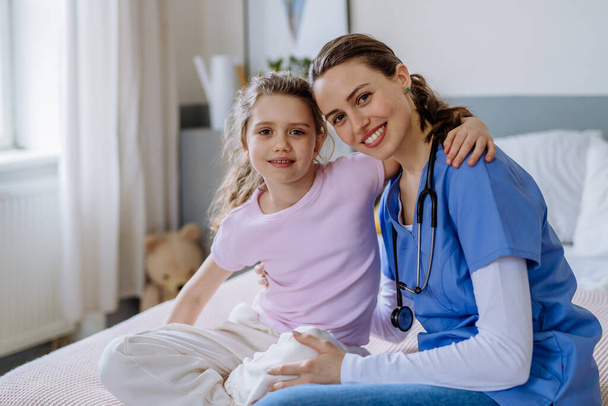 Молодий лікар піклується про маленьку дівчинку в лікарняній кімнаті
. - Фото, зображення
