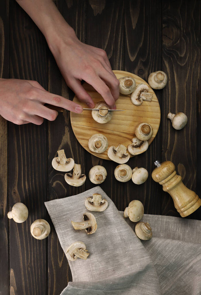 fresh large fragrant champignon mushrooms in a dark kitchen next to a knife and pepper shaker. for labels splash screens menu banners shop signs - Foto, Imagem