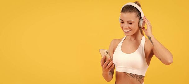 happy girl in listen music in headphones. fit your body. playlist for training. training mobile app. Woman isolated face portrait, banner with mock up copyspace - Foto, immagini