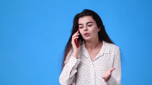 4k βίντεο ενός κοριτσιού που μιλάει συναισθηματικά στο τηλέφωνο πάνω από το μπλε φόντο. Έννοια των συναισθημάτων. - Πλάνα, βίντεο