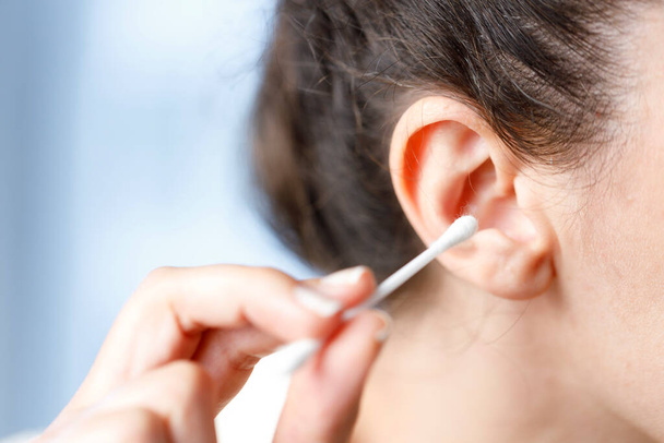 Woman about to use a cotton swab in her ear. Cleaning ear with cotton bu - Fotó, kép