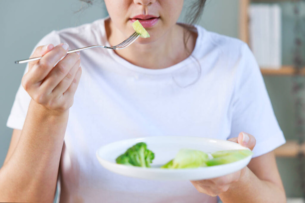Dieting problems. Eating disorder. Young woman eating fresh vegetables. Malnutrition harms health - Foto, Bild