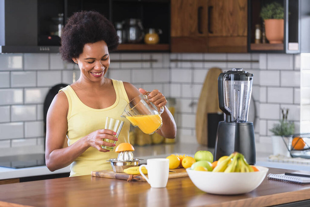 Afrikkalainen amerikkalainen nainen tekee appelsiinimehua - Valokuva, kuva