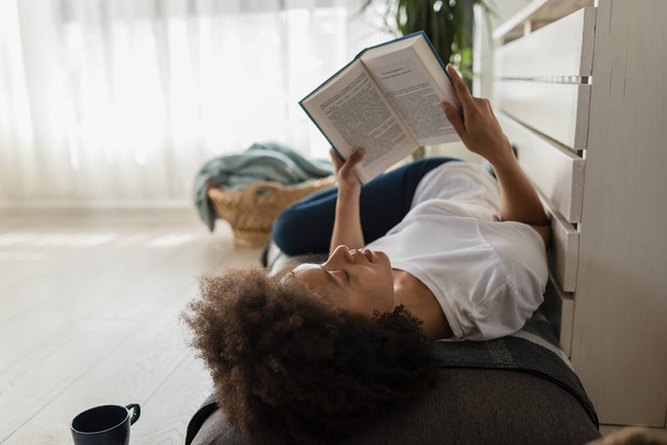 african american woman reading book at home - Фото, зображення