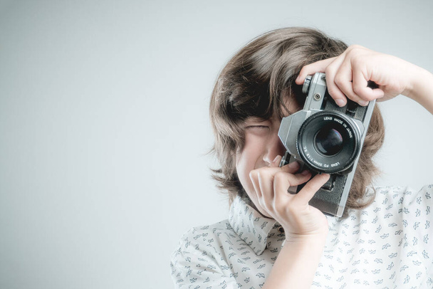 Boy with white shirt and blue details taking pictures with antique camera. - 写真・画像