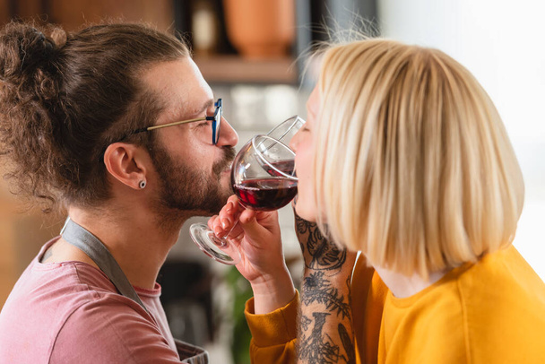Όμορφη νεαρή hipster αγάπη ζευγάρι ψήσιμο με κρασί στο σπίτι - Φωτογραφία, εικόνα