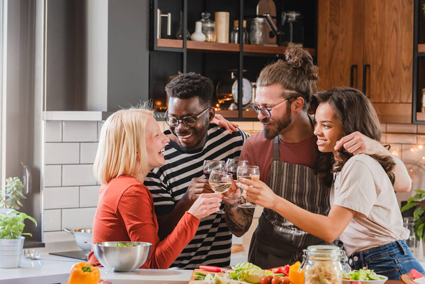 Νέοι διαφορετικοί άνθρωποι κάνουν πάρτι στο σπίτι, ετοιμάζοντας φαγητό, πίνοντας, μιλώντας και απολαμβάνοντας - Φωτογραφία, εικόνα
