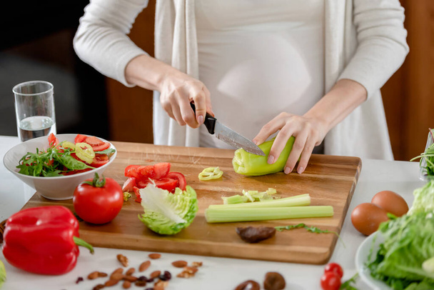 Mujer embarazada joven que prepara alimentos saludables con frutas y verduras - Foto, imagen