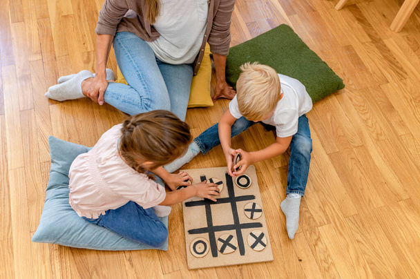 Mother playing with children a Tic-Tac-Toe game. Educational games for kids. Mother-children creative time together. - Fotoğraf, Görsel
