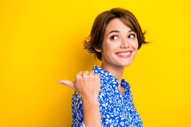 Photo of pretty dreamy woman dressed blue blouse looking pointing thumb back empty space isolated yellow color background. - Φωτογραφία, εικόνα