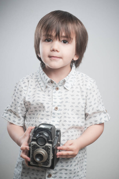 Poika valkoinen paita ja sininen yksityiskohtia ottaa kuvia antiikki kamera.   - Valokuva, kuva