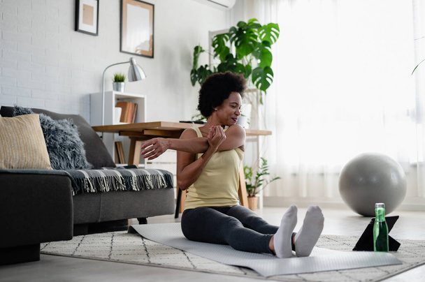 African-American woman doing exercises on the floor at her home. Trying to stay healthy and fit. - Fotografie, Obrázek
