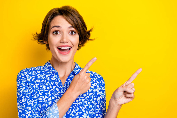Photo of shiny impressed woman dressed blue blouse pointing two fingers empty space isolated yellow color background. - Fotó, kép