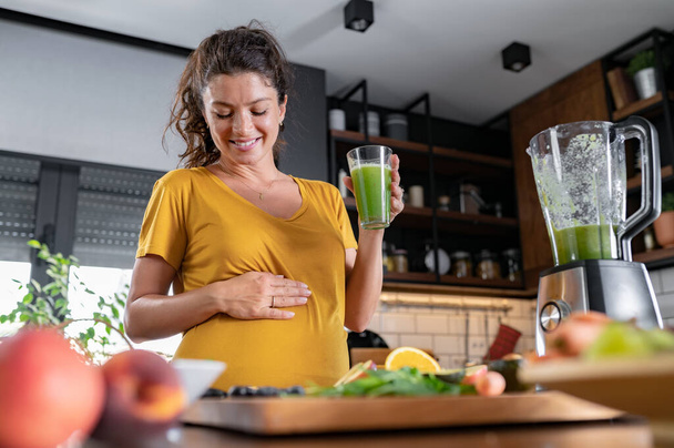 Mutfakta yemek yapan hamile bir kadın, sağlıklı beslenme konsepti. - Fotoğraf, Görsel