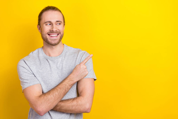 Photo of positive man wear grey trendy clothes arm presenting empty space good news novelty device shop isolated on yellow color background. - Фото, зображення
