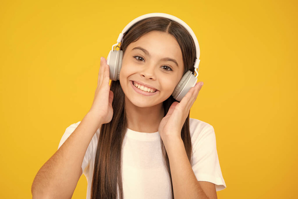 Happy teenager portrait. Funny kid girl 12, 13, 14 years old listen music with headphones. Teenage girl with headphones listening songs on headset earphone. Smiling girl - Foto, Bild