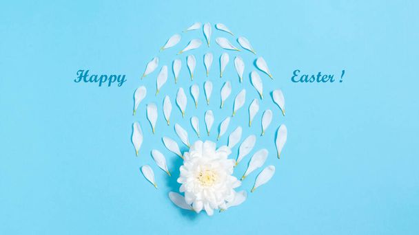 Veselé Velikonoce. Bílé přírodní okvětní lístky v blízkosti květu chryzantémy ve tvaru oválu nebo vajíčka. Velikonoční prázdniny. Pozdrav. Květinová modrá pozadí. - Fotografie, Obrázek