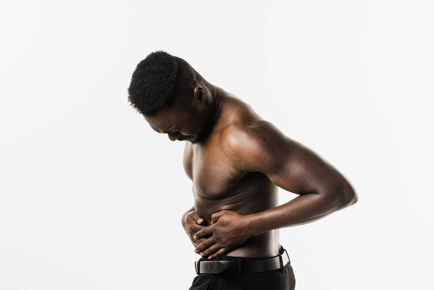 Uomo muscoloso afroamericano con malattia infiammatoria pelvica su sfondo bianco. Infezione da PID di uno o più organi riproduttivi superiori, inclusi utero, tube e ovaie di Falloppio - Foto, immagini