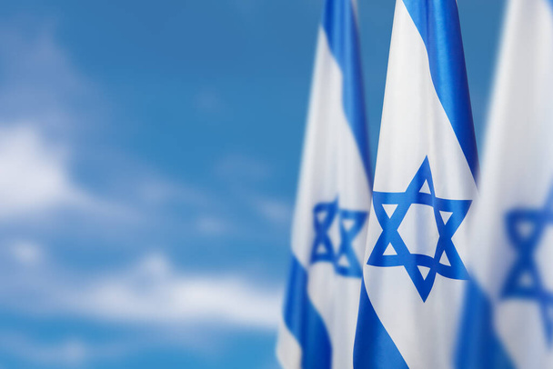 Israel flags with a star of David over cloudy sky background. Patriotic concept about Israel with national state symbols. Banner with place for text. - Φωτογραφία, εικόνα
