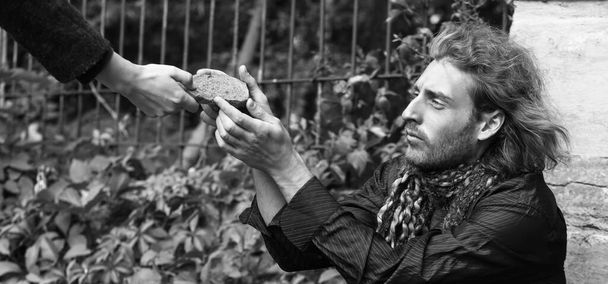 屋外で貧しいホームレスの男にパンを与える女性 - 写真・画像