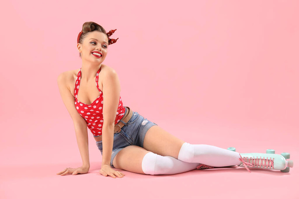 Young pin-up woman in roller skates on pink background - Fotografie, Obrázek