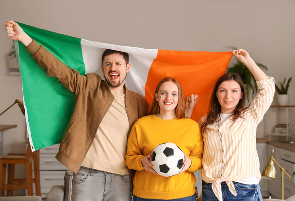 Amigos felizes com bandeira da Irlanda e bola de futebol em casa - Foto, Imagem