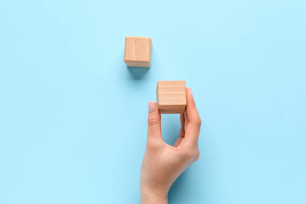 Woman with wooden cubes on blue background - 写真・画像