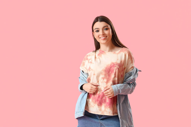 Stylish young woman in tie-dye t-shirt on pink background - Foto, Imagem