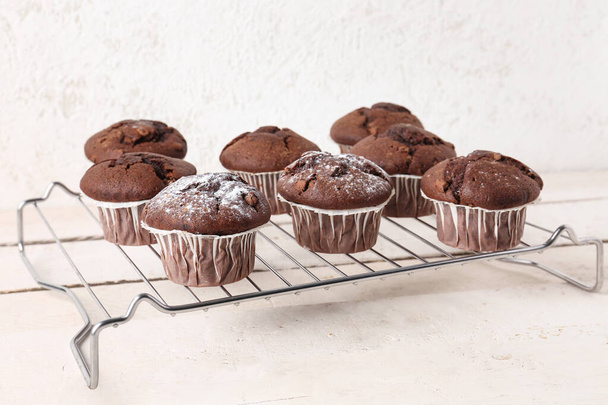Rejilla con sabrosos cupcakes de chocolate sobre fondo claro - Foto, Imagen