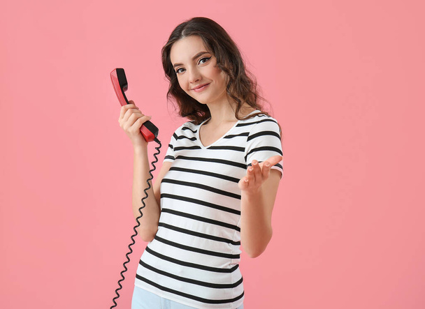 Young woman with phone receiver on pink background - Fotografie, Obrázek