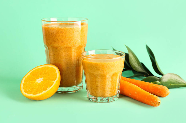 Óculos de smoothie saudável com laranja e cenouras em fundo turquesa - Foto, Imagem