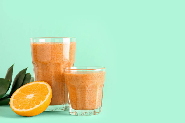 Glasses of healthy smoothie with orange and carrots on turquoise background - Photo, Image