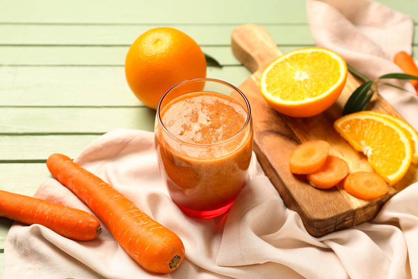 Copo de smoothie laranja saudável e ingredientes em mesa de madeira verde - Foto, Imagem