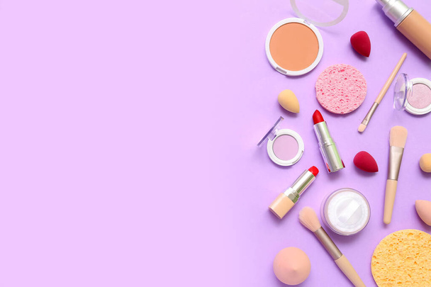 Cosméticos decorativos com pincéis de maquiagem e esponjas sobre fundo lilás - Foto, Imagem