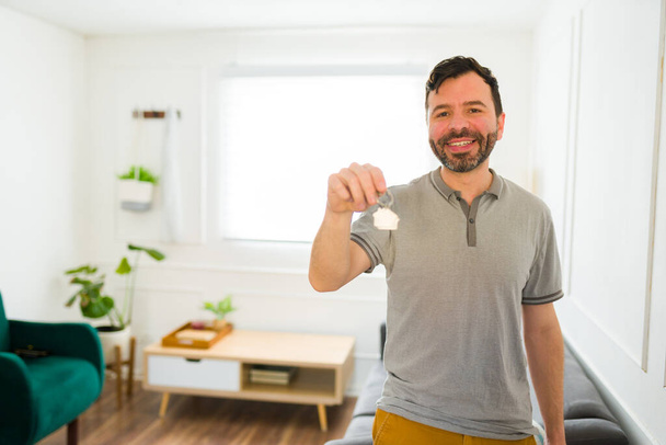 Кавказский привлекательный мужчина выглядит взволнованным после получения ключей от своего нового дома после переезда  - Фото, изображение