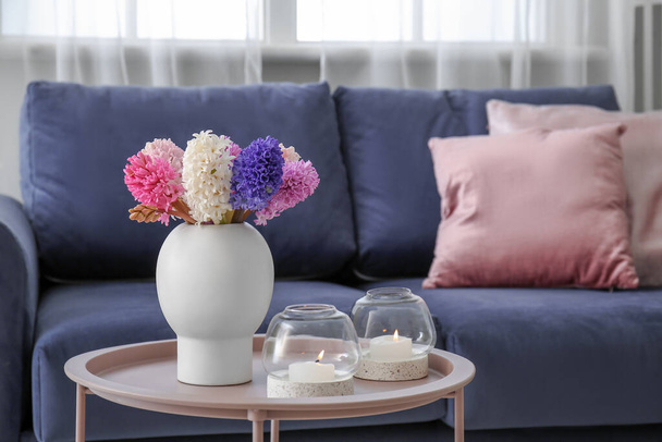 Vase with beautiful hyacinth flowers and burning candles on coffee table in living room - Fotografie, Obrázek