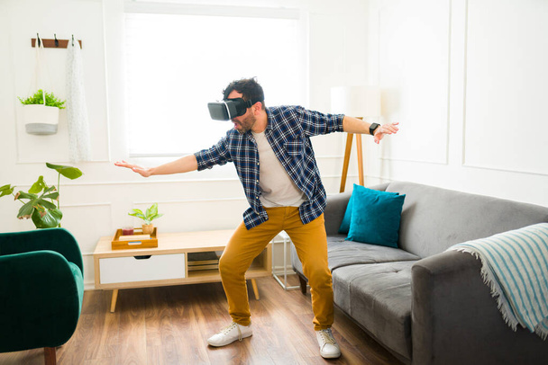 Fun caucasian man in his 30s having fun playing with virtual reality glasses during a leisure time at home - Foto, afbeelding