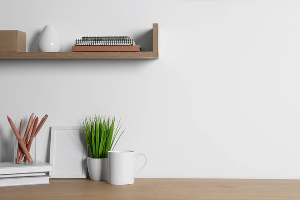 Comfortable workplace with wooden desk near white wall at home - Foto, imagen